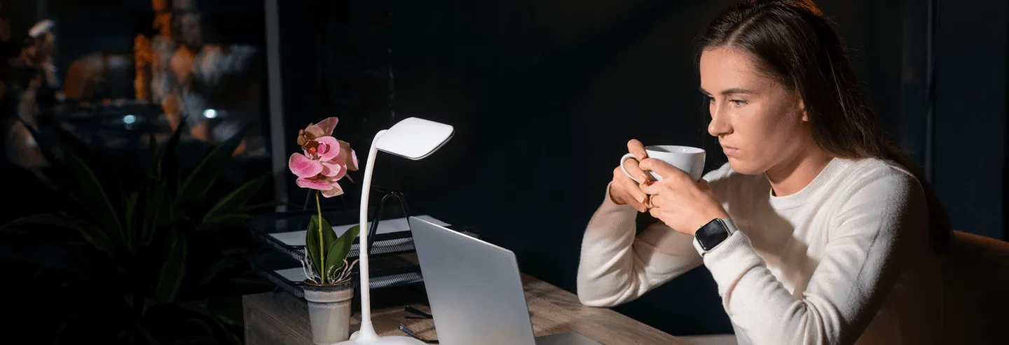 woman holding cup in front of a laptop